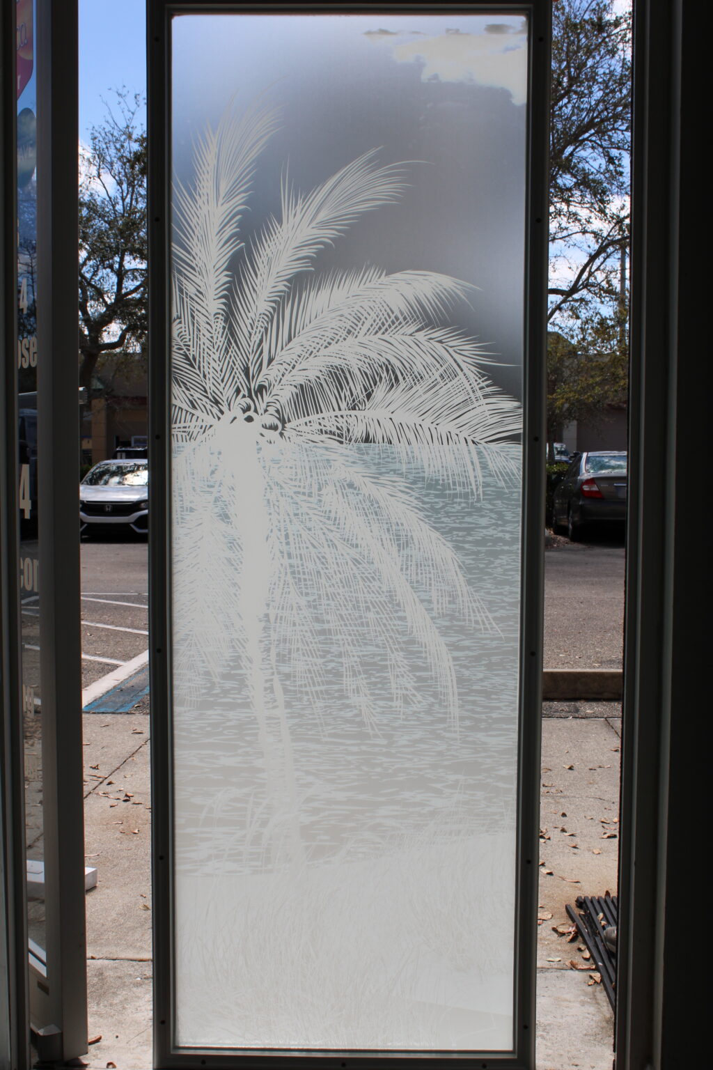 Frosted glass film with etched palm tree and beach scene design, offering a coastal decorative style with privacy.