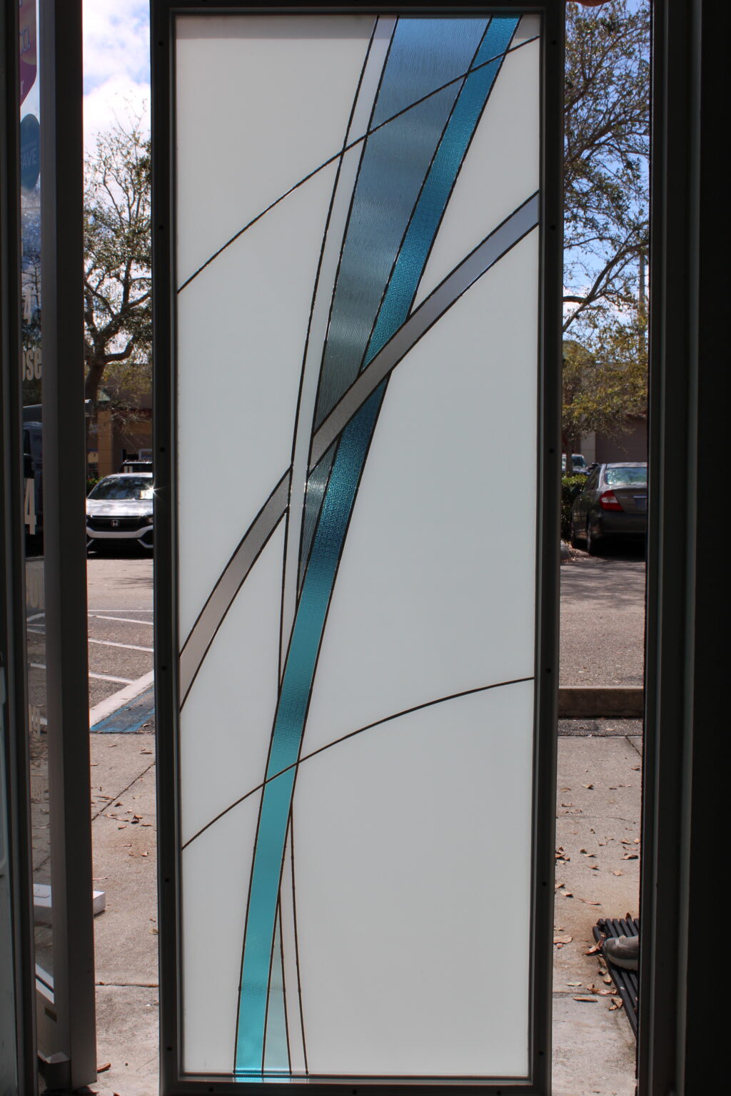 Elegant frosted glass panel with intersecting aqua blue and textured clear curved lines for a modern decorative touch.